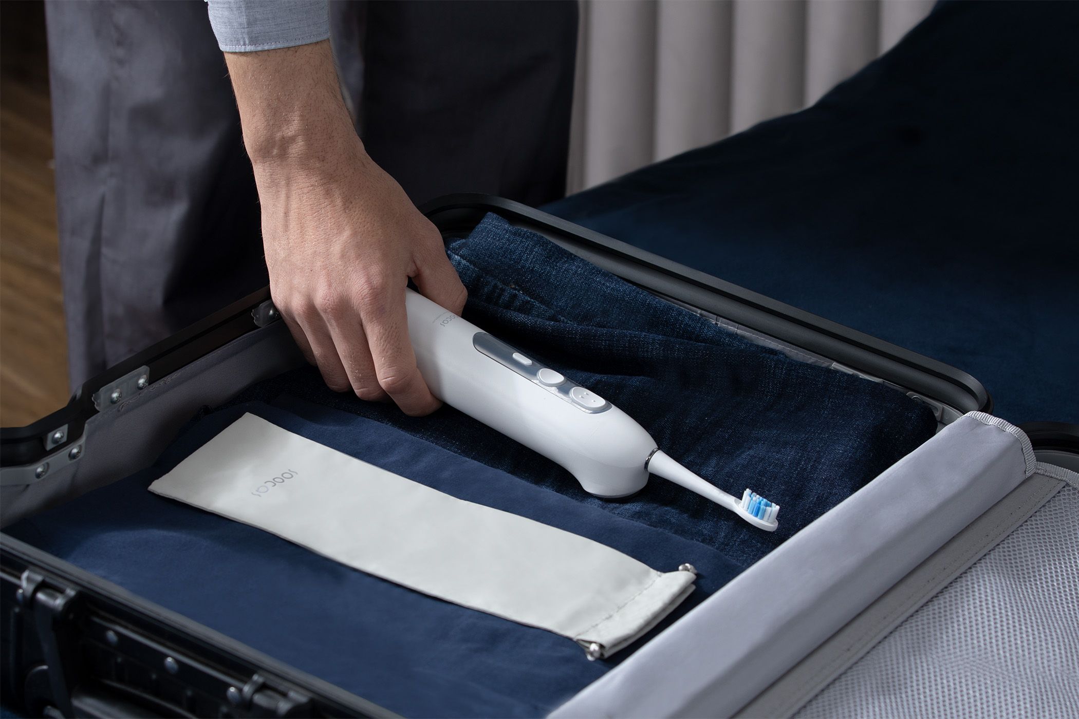 A man packs the Soocas Neos toothbrush in his suitcase.