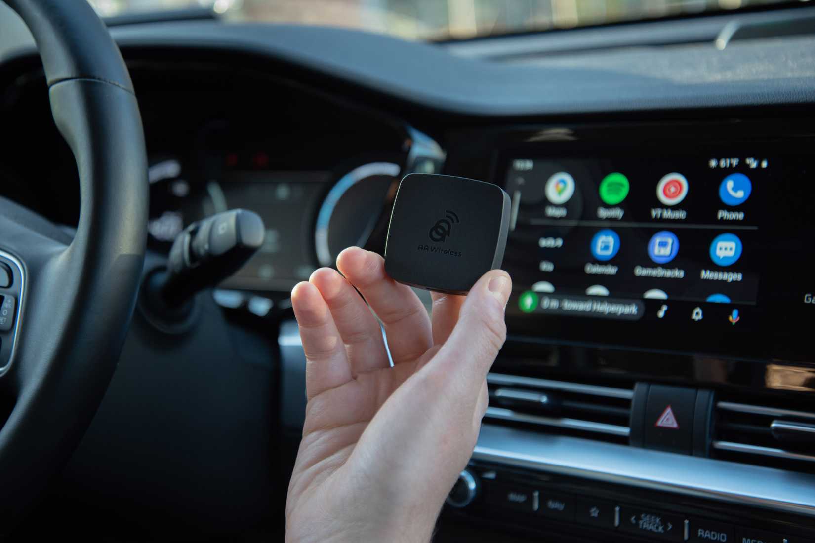 A man holding the AAWireless adapter connected to Android Auto 