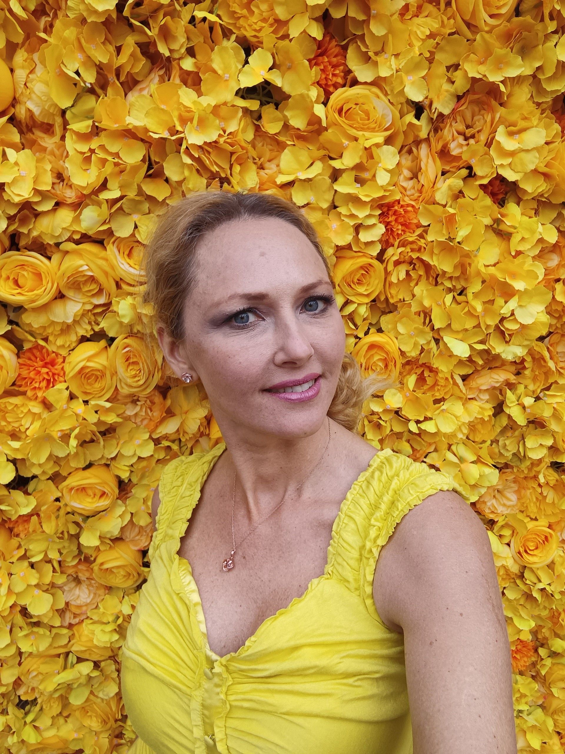 an selfie taken by a lady with a flower wall background